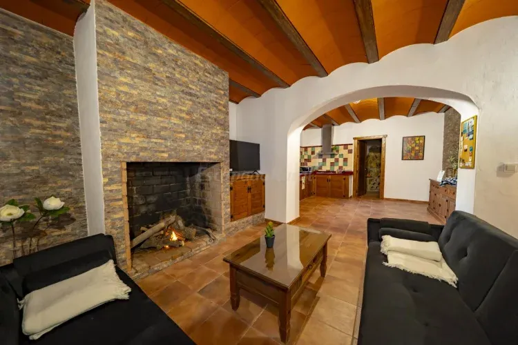Imagen de La primera estancia de la Casa corresponde a un espacio abierto que integra el salón y la cocina. Cuenta con dos sofás-cama que completarían junto con las trece plazas restantes, un alojamiento para 15 personas. Además, hay una gran chimenea, un mueble recibidor y una cocina equipada al completo. Tiene una campana extractora de humos, lavavajillas, nevera, cocina de gas, tostador, cafetera y una amplia variedad de utensilios (cazos, sartenes, ollas, cobertera, vajilla, platos, etc)