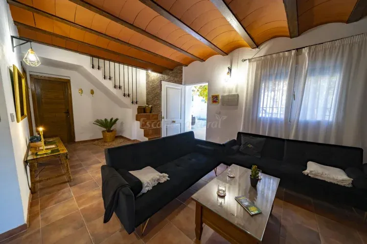 Imagen de La primera estancia de la Casa corresponde a un espacio abierto que integra el salón y la cocina. Cuenta con dos sofás-cama que completarían junto con las trece plazas restantes, un alojamiento para 15 personas. Además, hay una gran chimenea, un mueble recibidor y una cocina equipada al completo. Tiene una campana extractora de humos, lavavajillas, nevera, cocina de gas, tostador, cafetera y una amplia variedad de utensilios (cazos, sartenes, ollas, cobertera, vajilla, platos, etc)