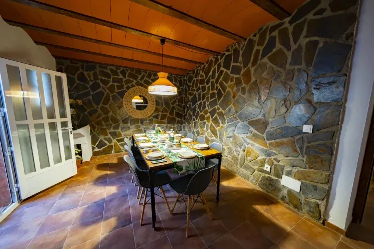 Imagen de El comedor, ubicado en la misma planta que la cocina y el salón, tiene una espaciosa mesa central con diez sillas. Sin embargo, la capacidad puede ampliarse para que hasta catorce comensales la usen sin problema. Junto al comedor, se encuentra el acceso al patio interior de la Casa